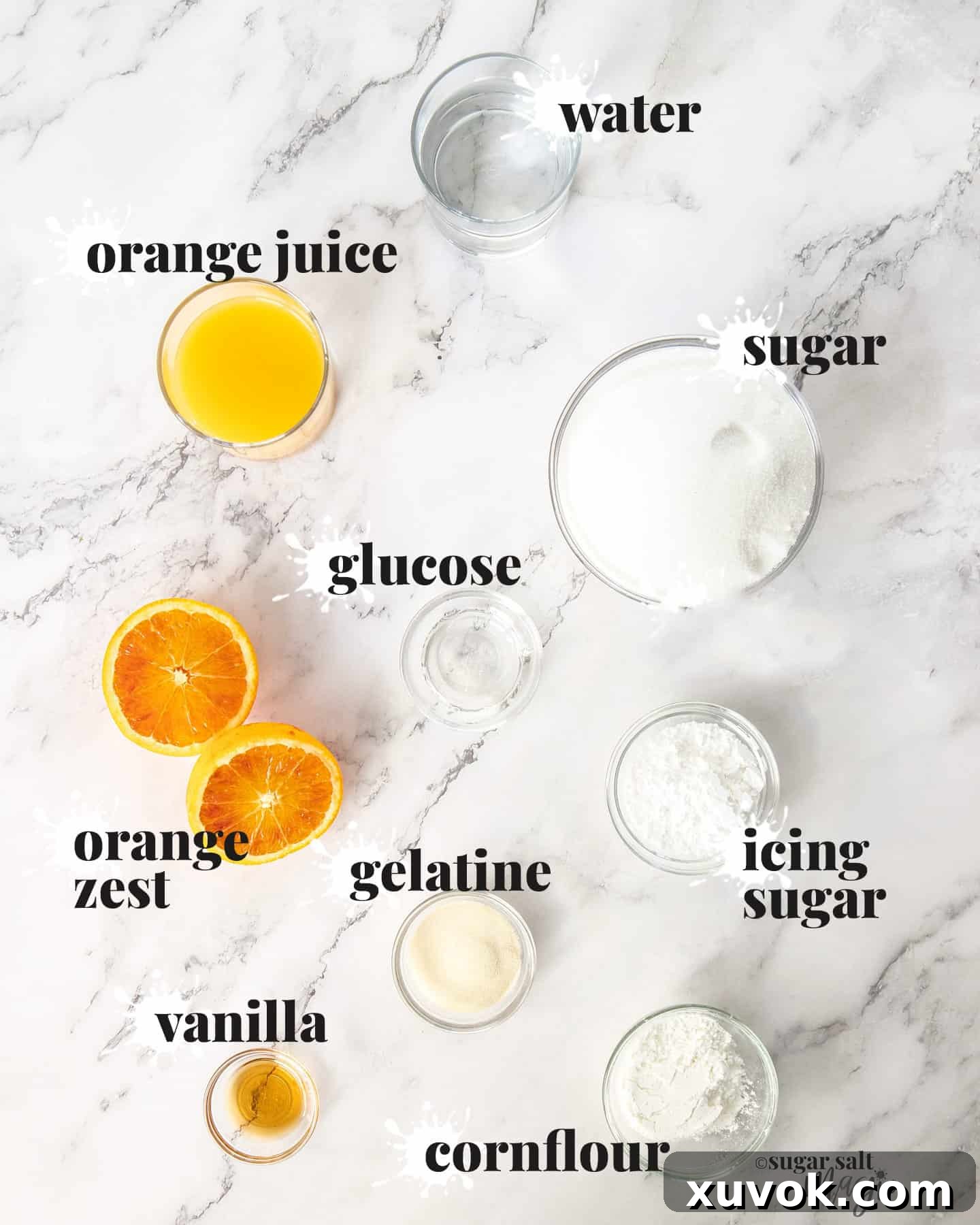 A flat lay photograph showcasing the essential ingredients for making homemade orange marshmallows, neatly arranged on a sleek marble countertop.