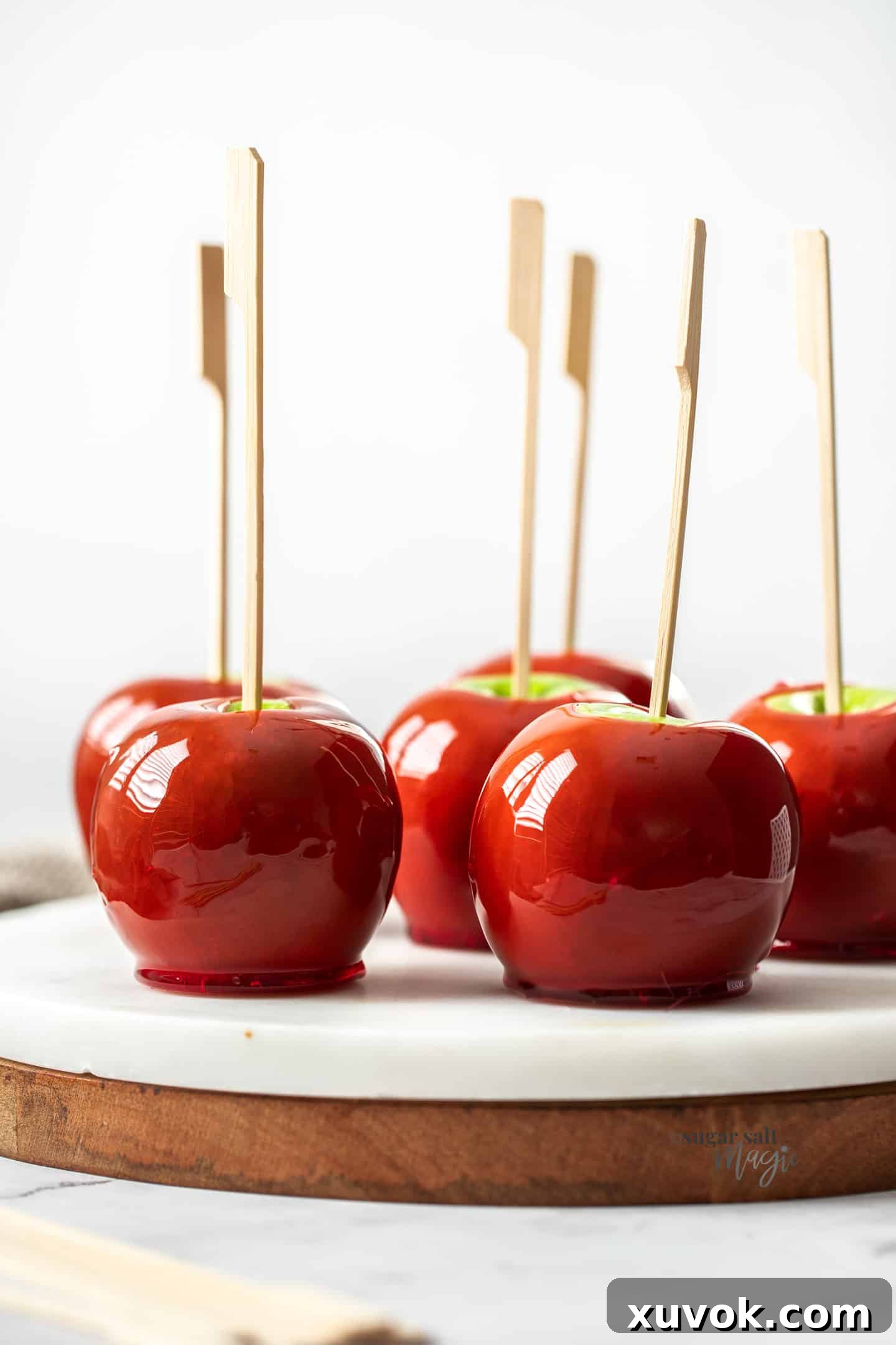 Close up of red toffee apples sitting on a marble platter.