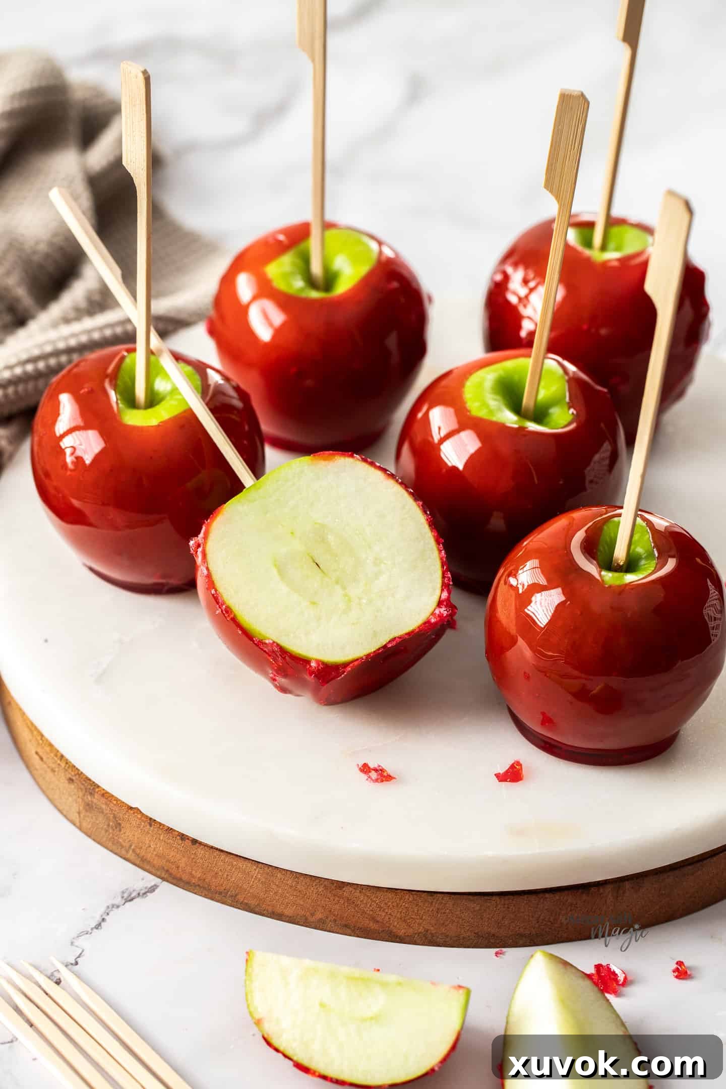 Red toffee apples, with one cut in half on a marble platter.