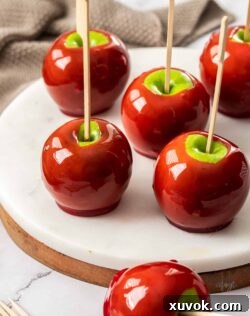 6 red toffee apples on a white marble platter.