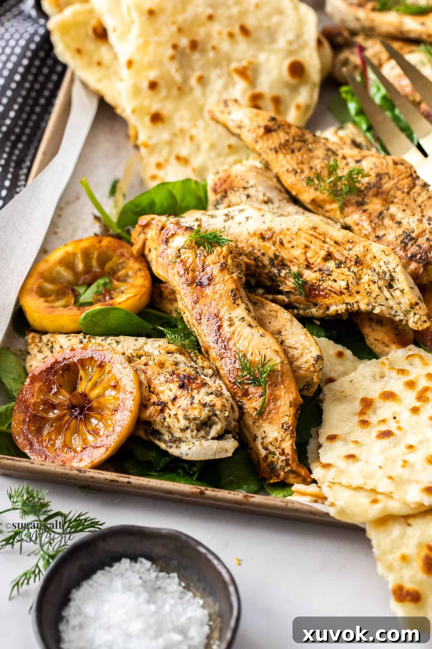 A batch of perfectly cooked, golden-brown Greek chicken pieces resting on a baking tray after being pan-fried, ready to be served or added to a meal.