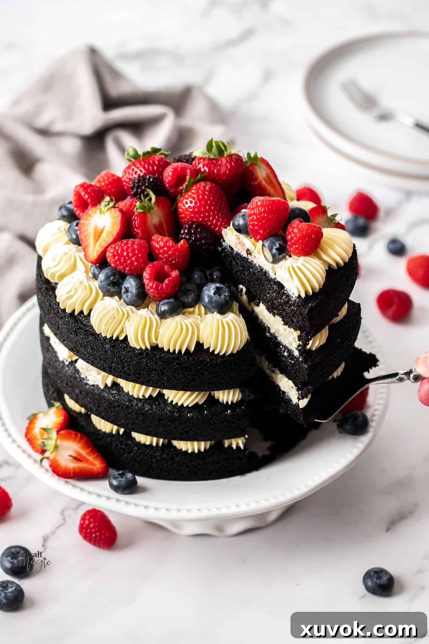 Top down view of a 3 tier black velvet cake topped with fresh berries, beautifully arranged and ready to be served.