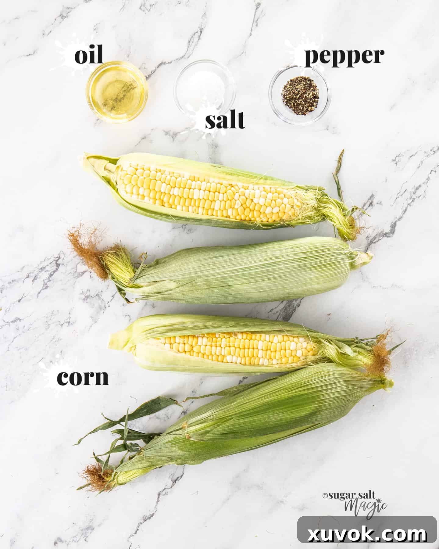 A simple array of ingredients for air fryer corn, including fresh corn cobs, a bottle of olive oil, salt, and pepper, all arranged on a elegant marble countertop.