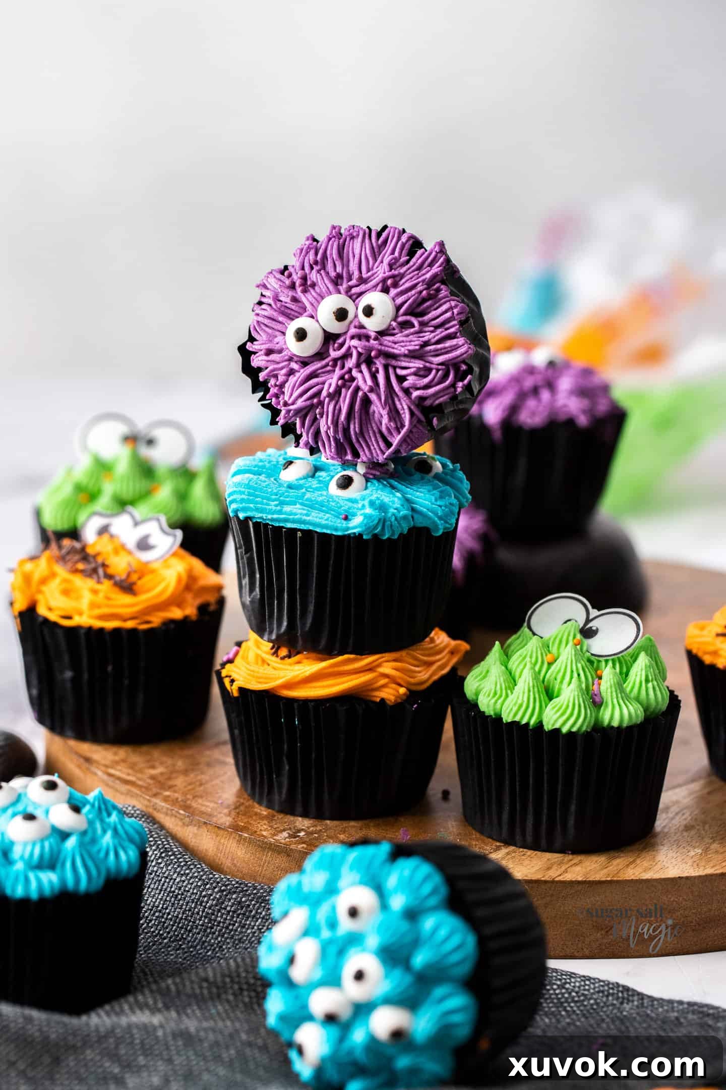 A stack of 3 cupcakes with one facing the camera on top. These adorable monster cupcakes are perfect Halloween treats or for birthday parties. Moist and tender dark chocolate cupcakes, topped with a fun, colourful frosting and beady little eyes.