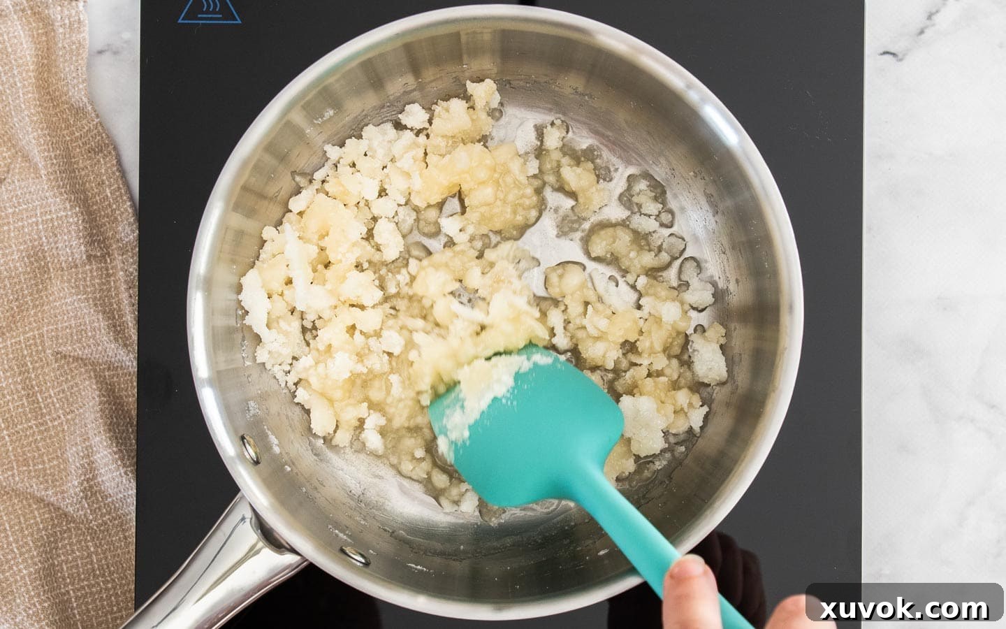 Sugar clumps melting and turning golden in a saucepan, beginning the caramelization process.