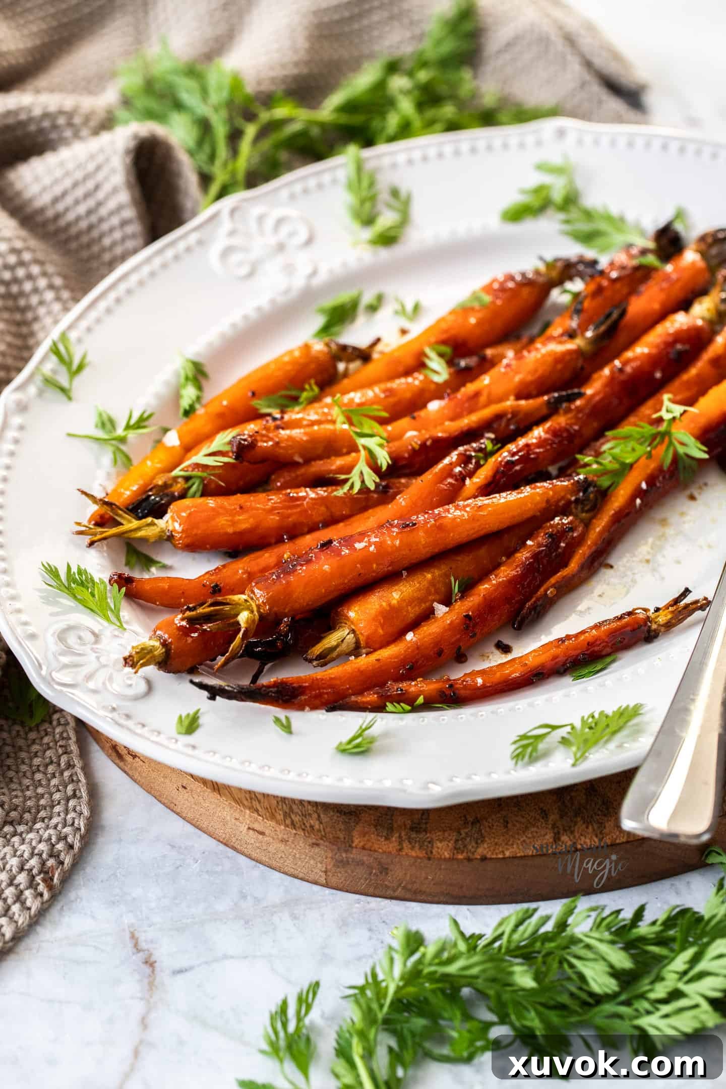 A batch of roasted baby carrots on a white and wooden platter.