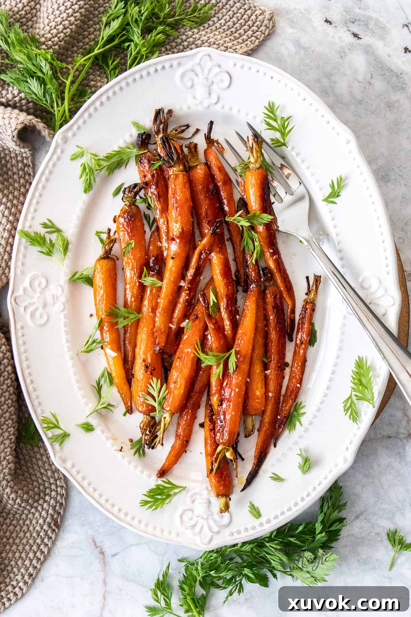 A batch of roasted baby carrots on a white platter.