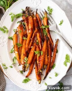 A batch of roasted baby carrots on a white platter.