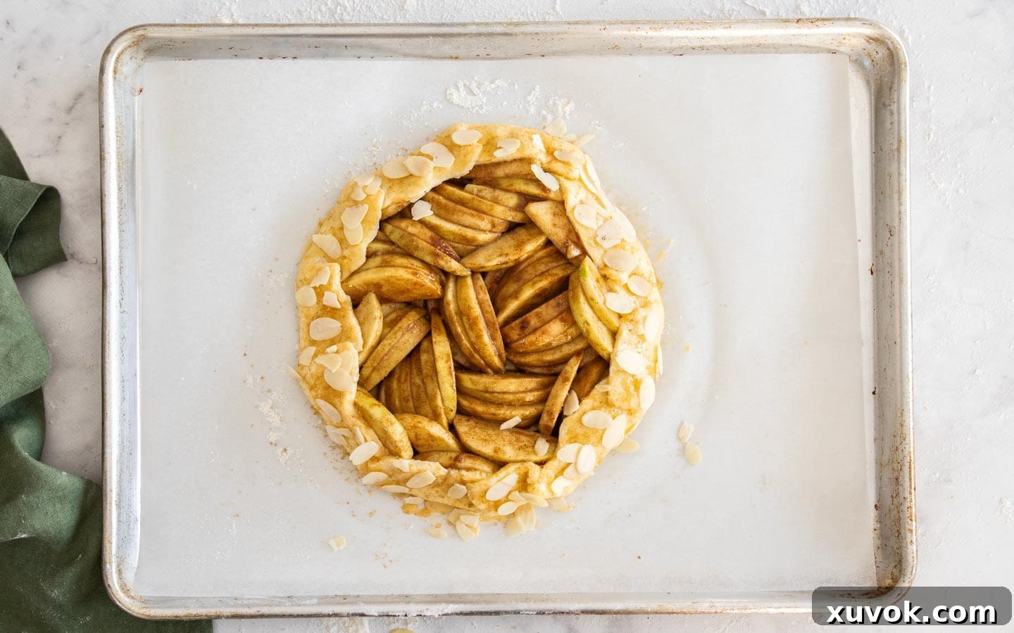 The edges of the crostata dough, brushed with egg wash and topped with demerara sugar and almonds.