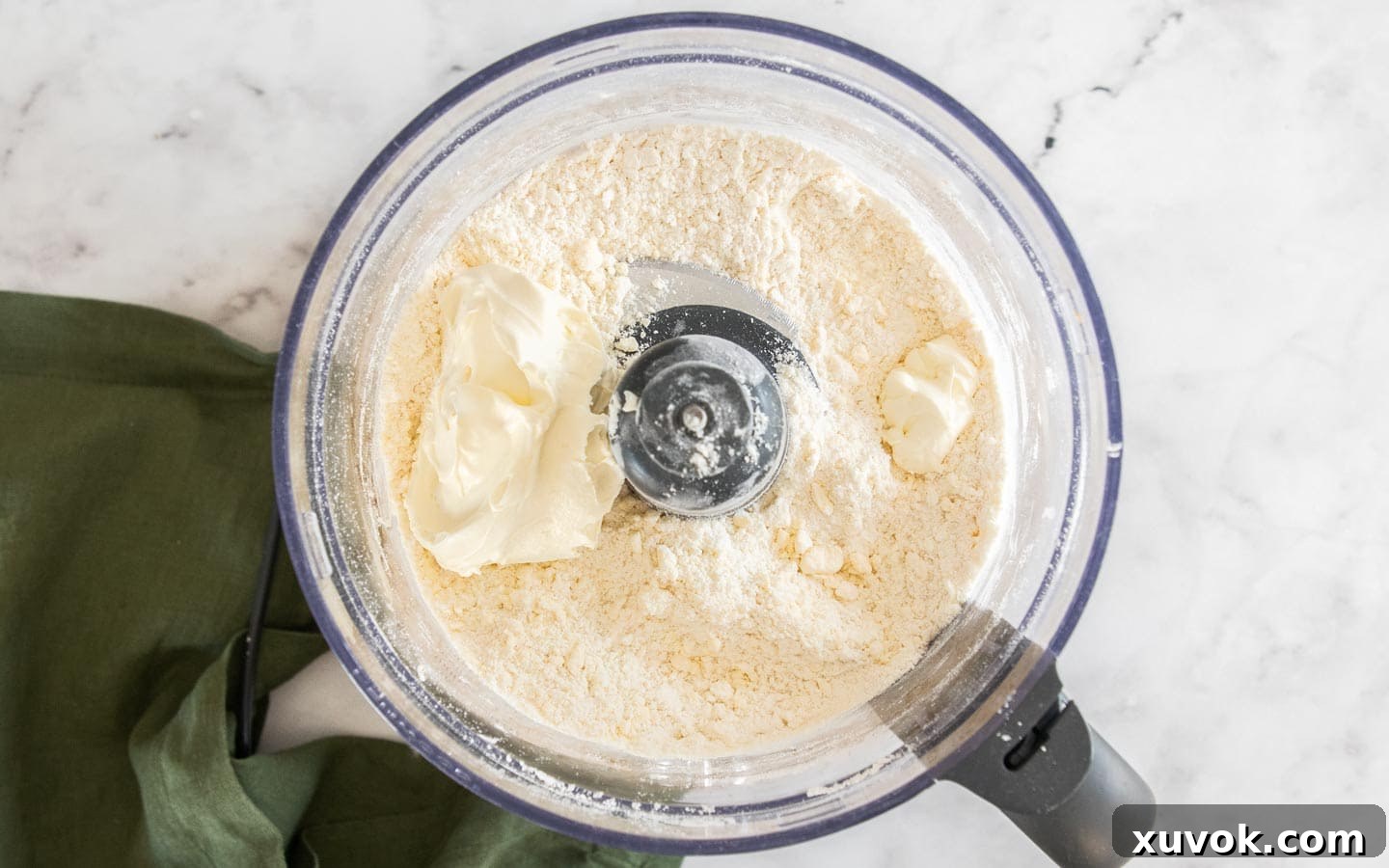 Sour cream being added to the pastry dough in a food processor, ready to be pulsed.