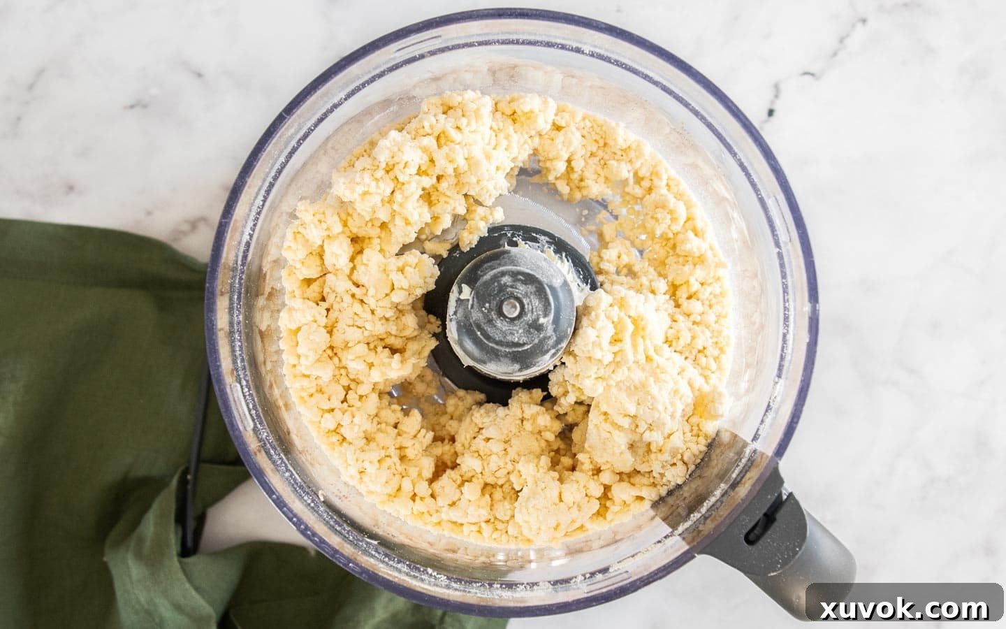 The crostata dough has formed into clumps in the food processor, indicating it's ready.