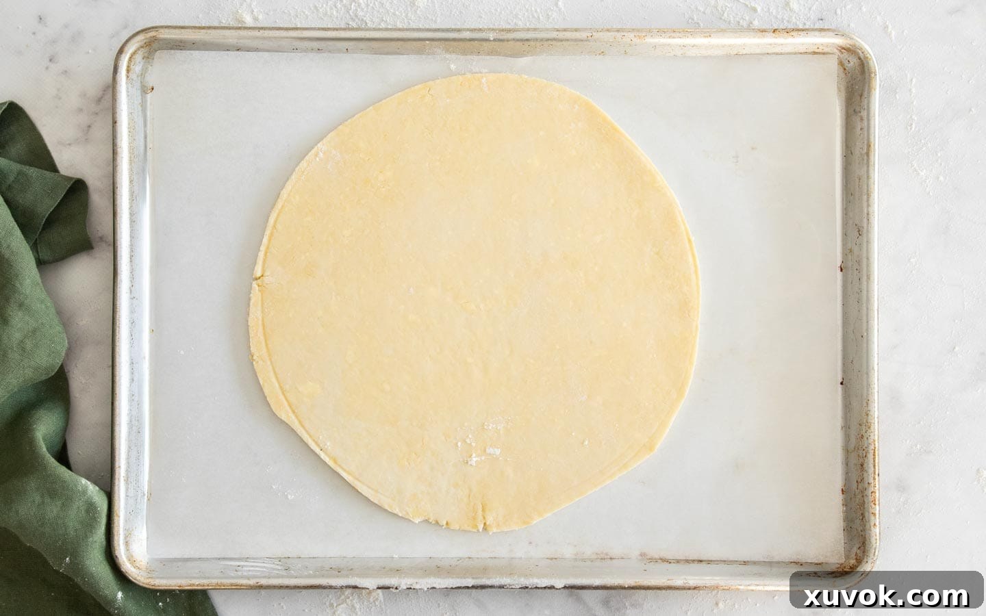 The crostata dough perfectly rolled out into a round on a baking sheet, ready for filling.