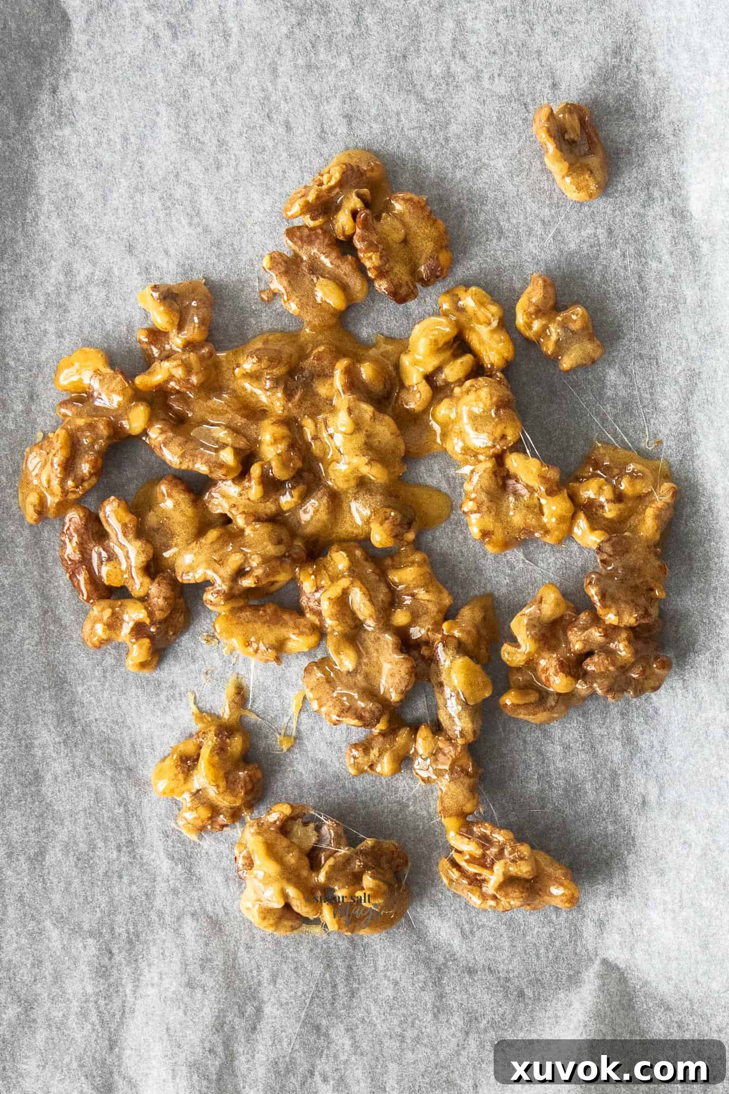 A batch of candied walnuts on a sheet of baking paper.