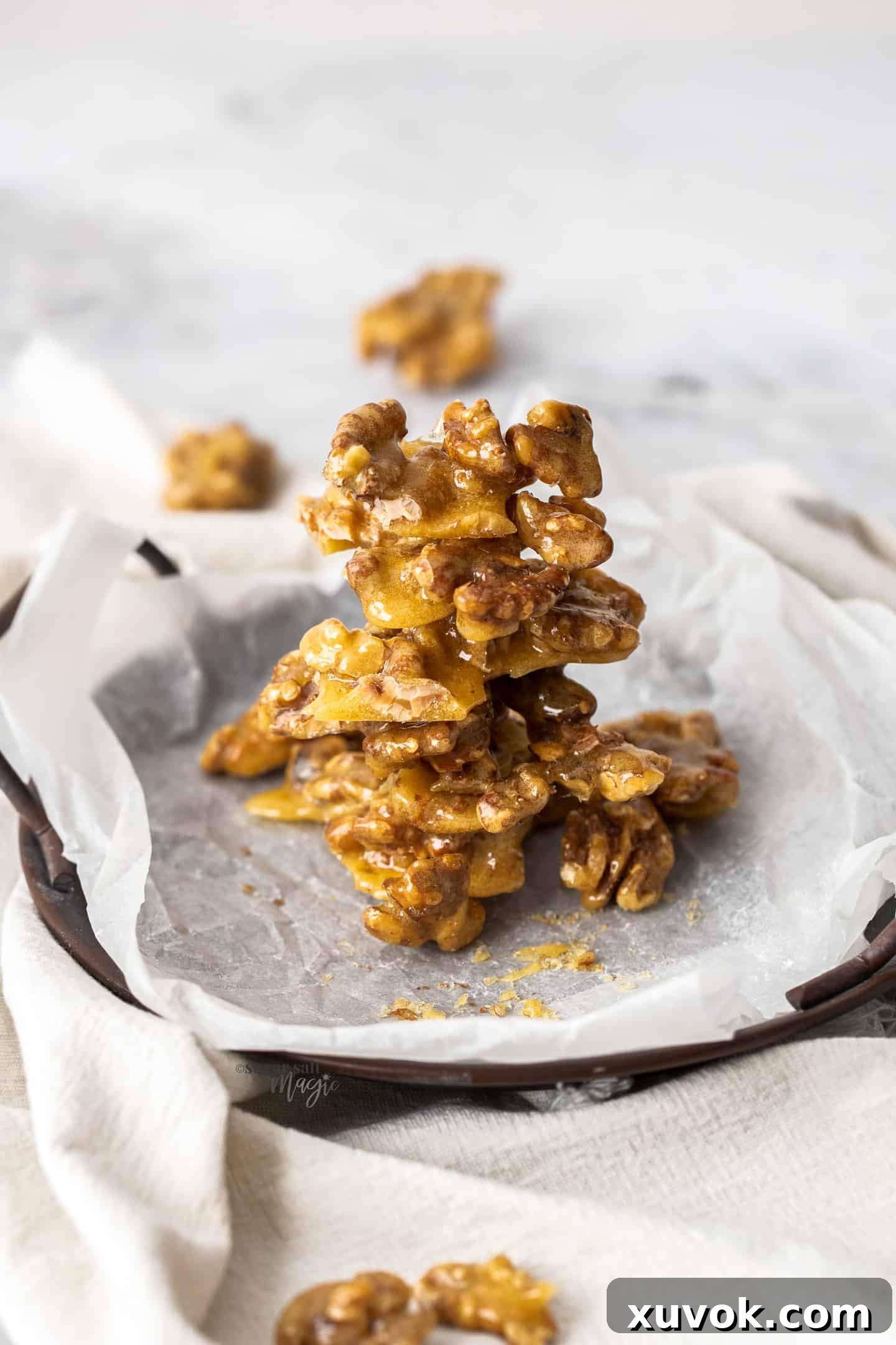 Candied walnuts stacked up on a small dark tray.