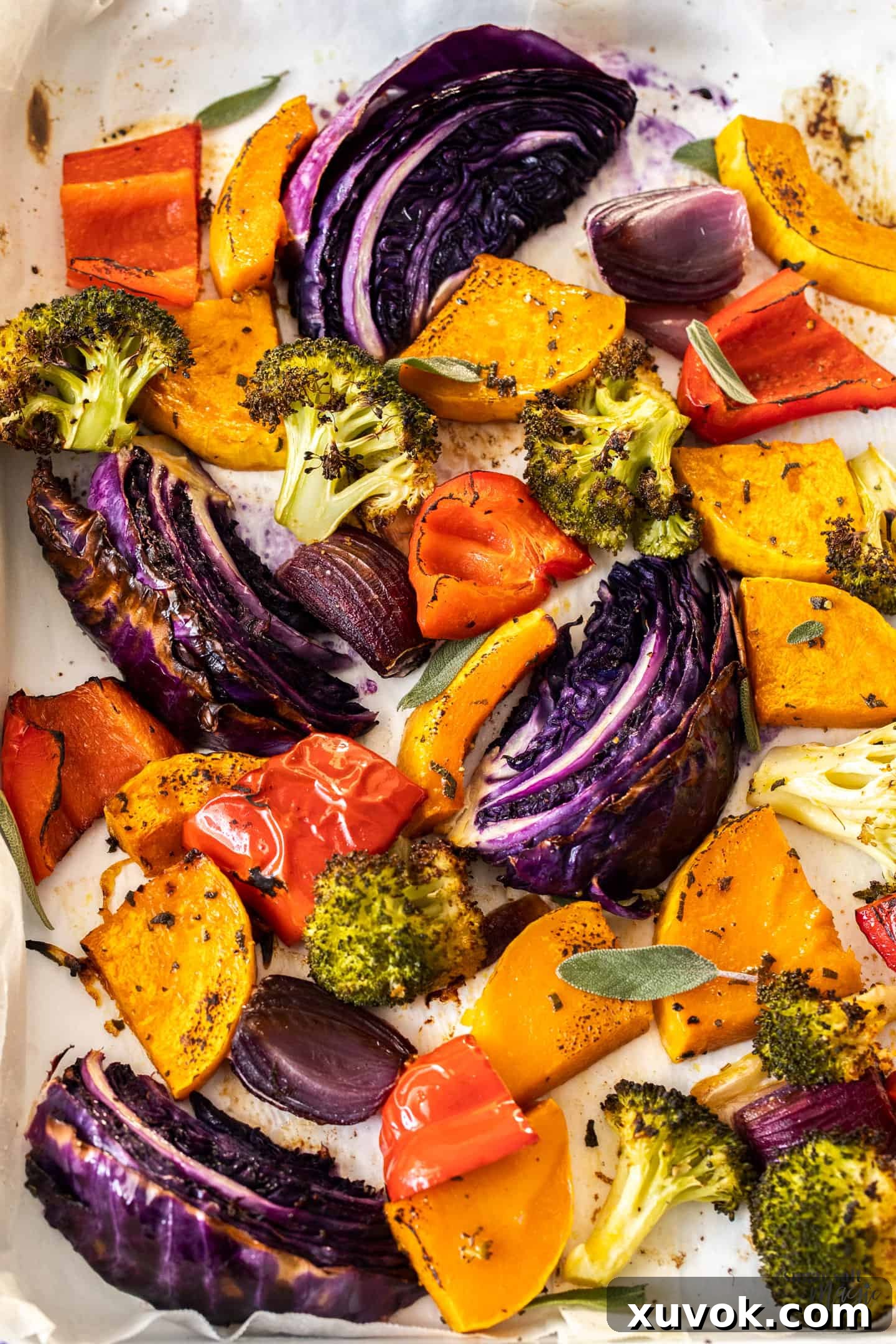 A vibrant assortment of beautifully roasted vegetables spread across a metal sheet pan, showcasing their golden-brown edges.