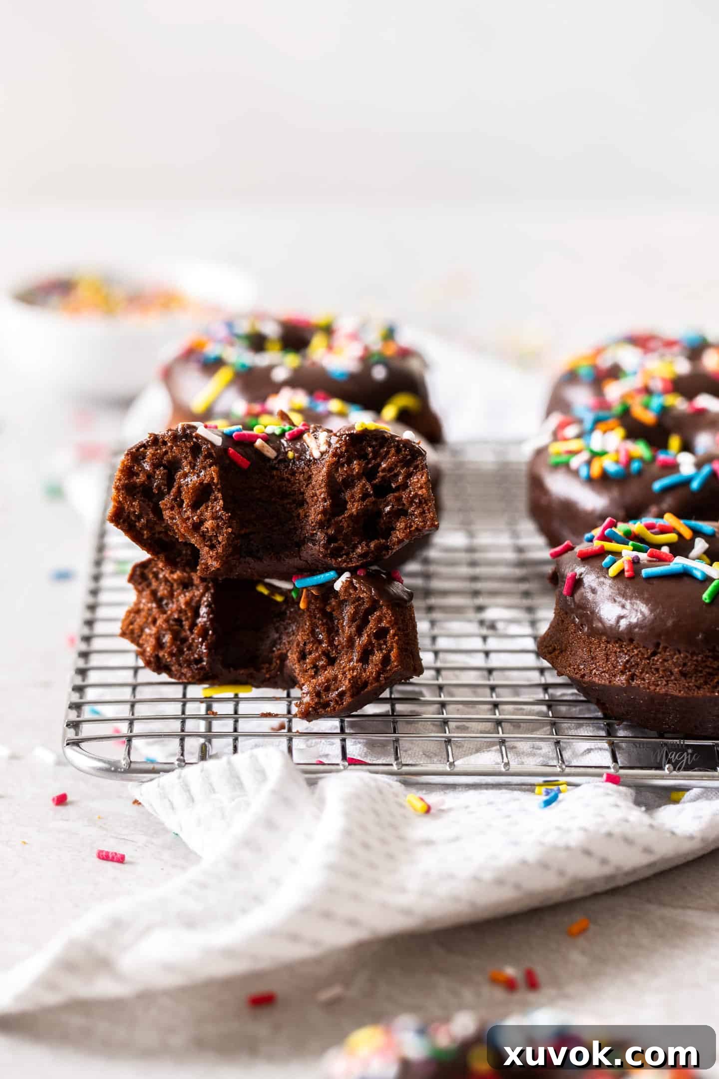 A baked chocolate cake donut broken in half, revealing its moist, fluffy texture inside, indicating perfect tenderness.