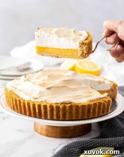 A slice of lemon meringue pie being held above the rest of the pie.