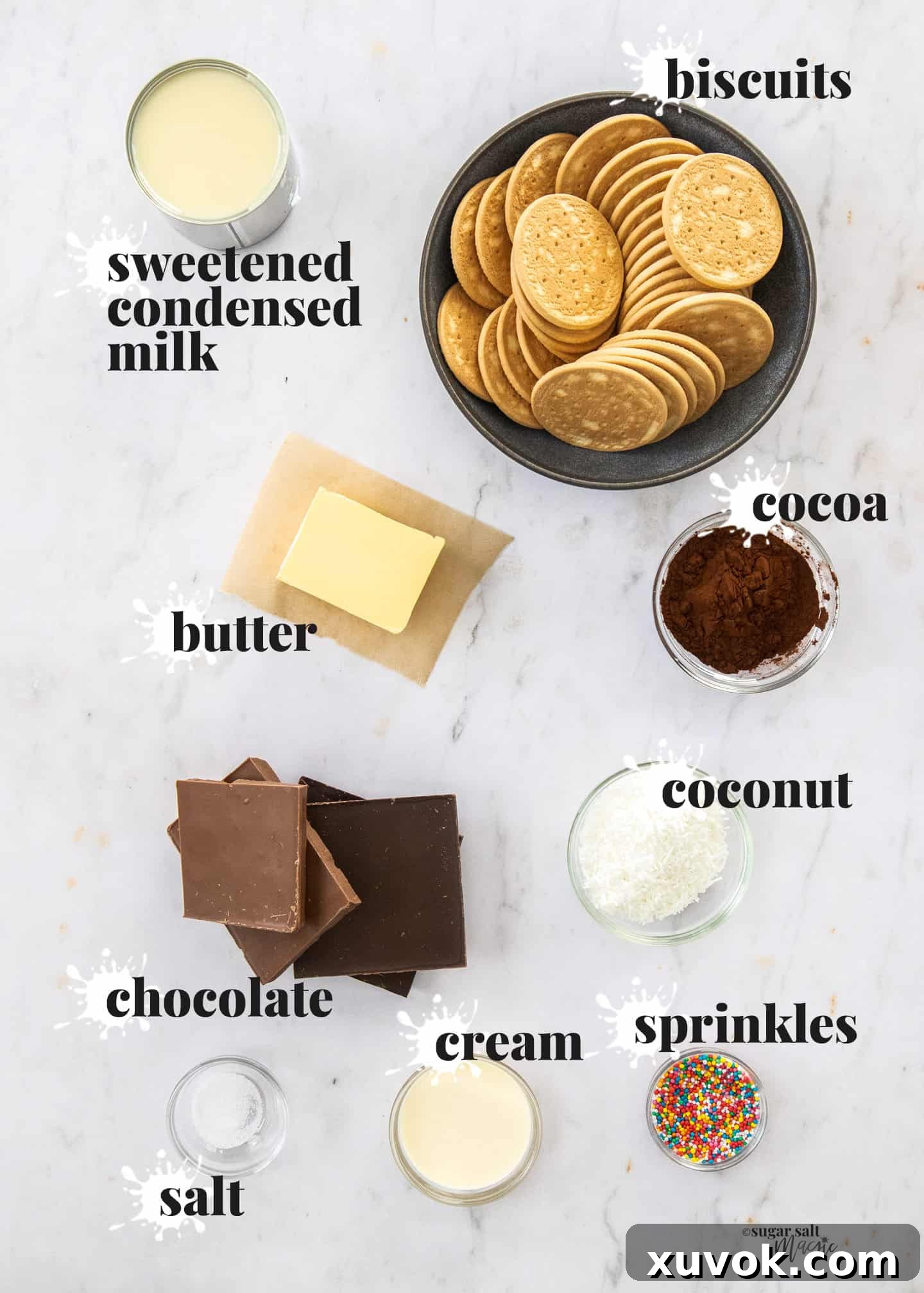 A flat lay of ingredients for chocolate hedgehog slice arranged on a marble surface, including biscuits, chocolate, butter, condensed milk, and cocoa powder.