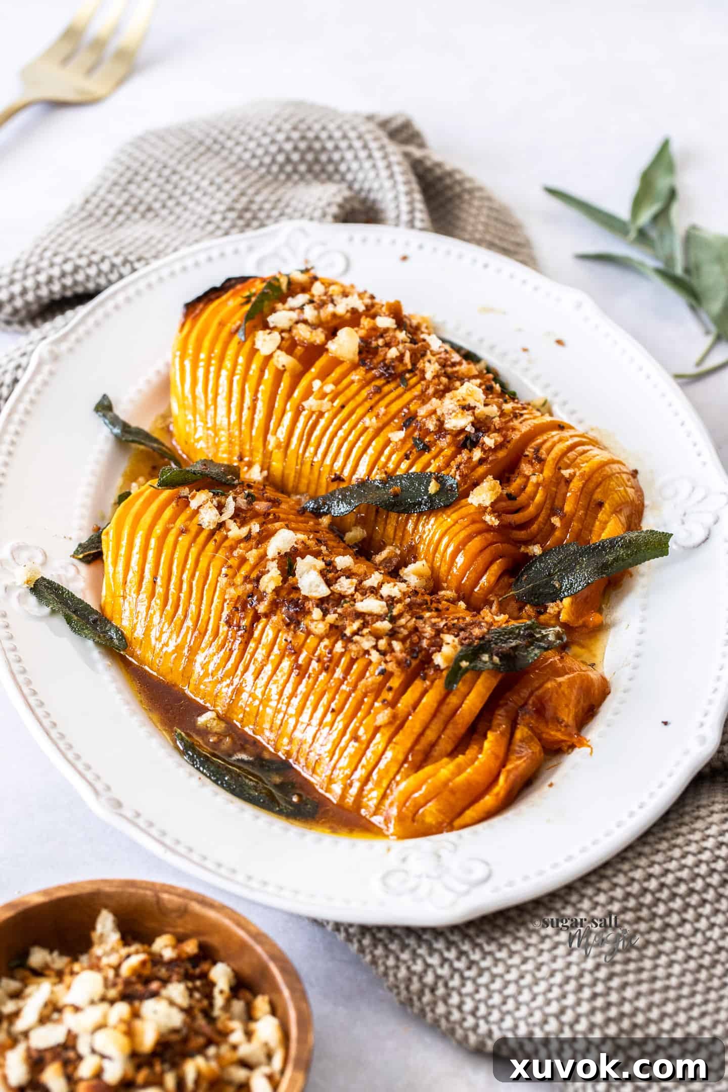 Two pieces of roasted hasselback butternut squash, beautifully plated on a white platter, ready to be served.