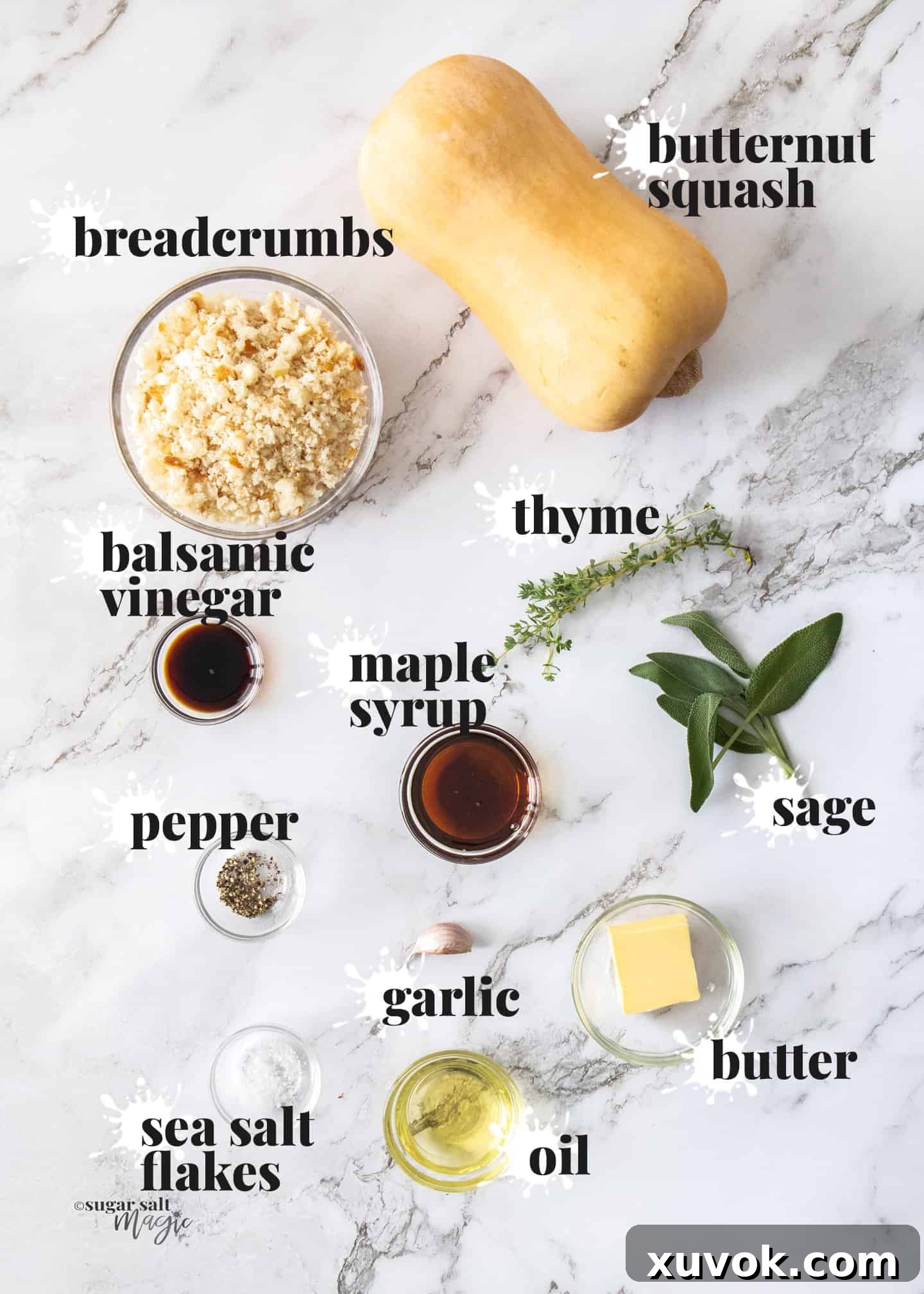 Ingredients for hasselback butternut squash laid out on a white marble surface, including squash, herbs, butter, and spices.