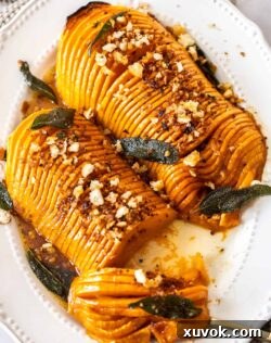 Two pieces of roasted hasselback butternut squash, with some cut away, on a white platter.