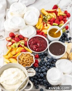 A board filled with meringue shells, sauces and fruit.
