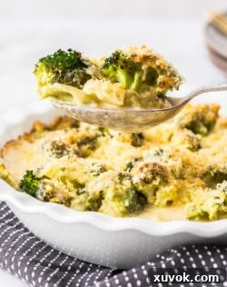 A serving spoon lifting broccoli cheese from a dish.