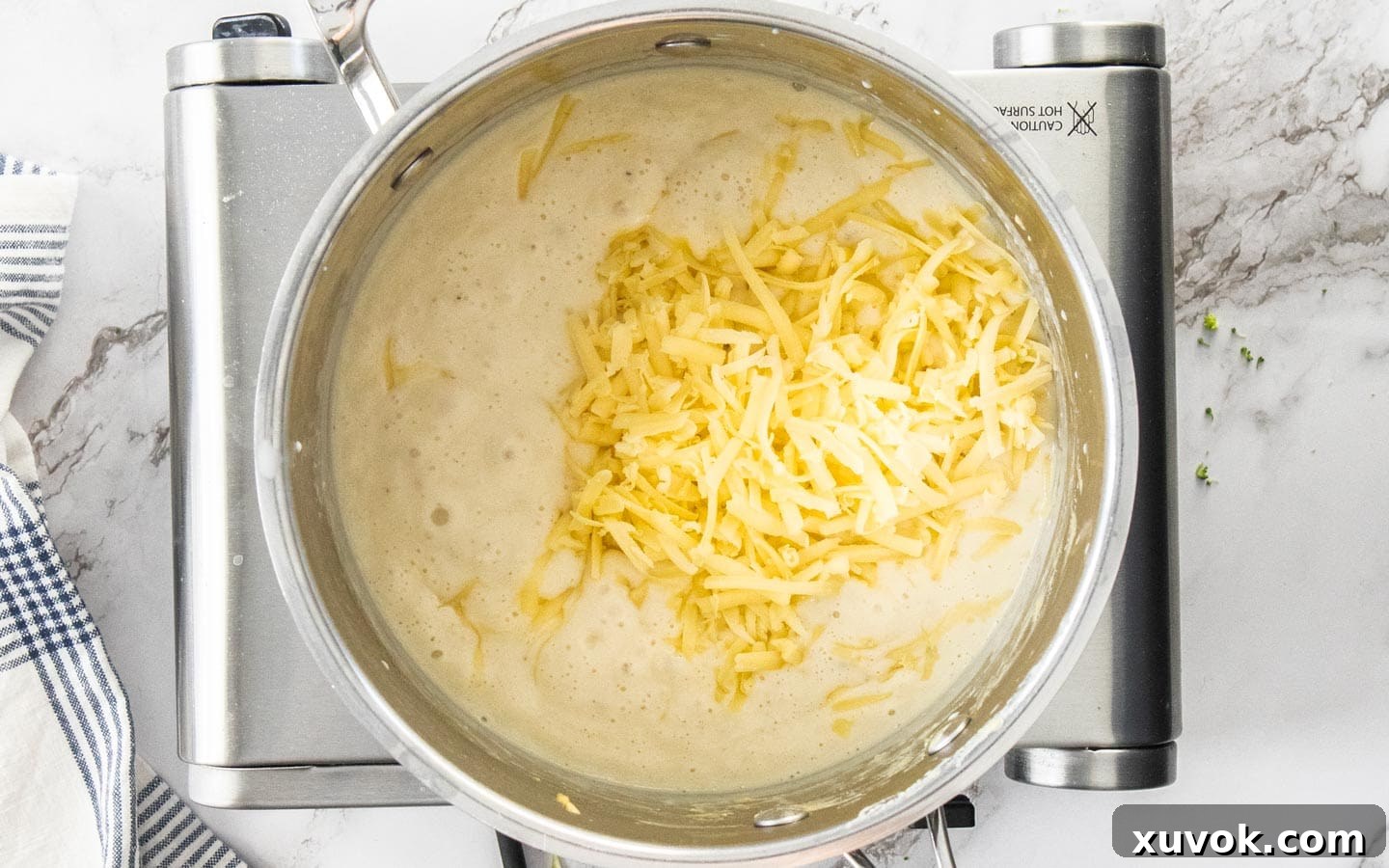 Adding the cheese to the saucepan.