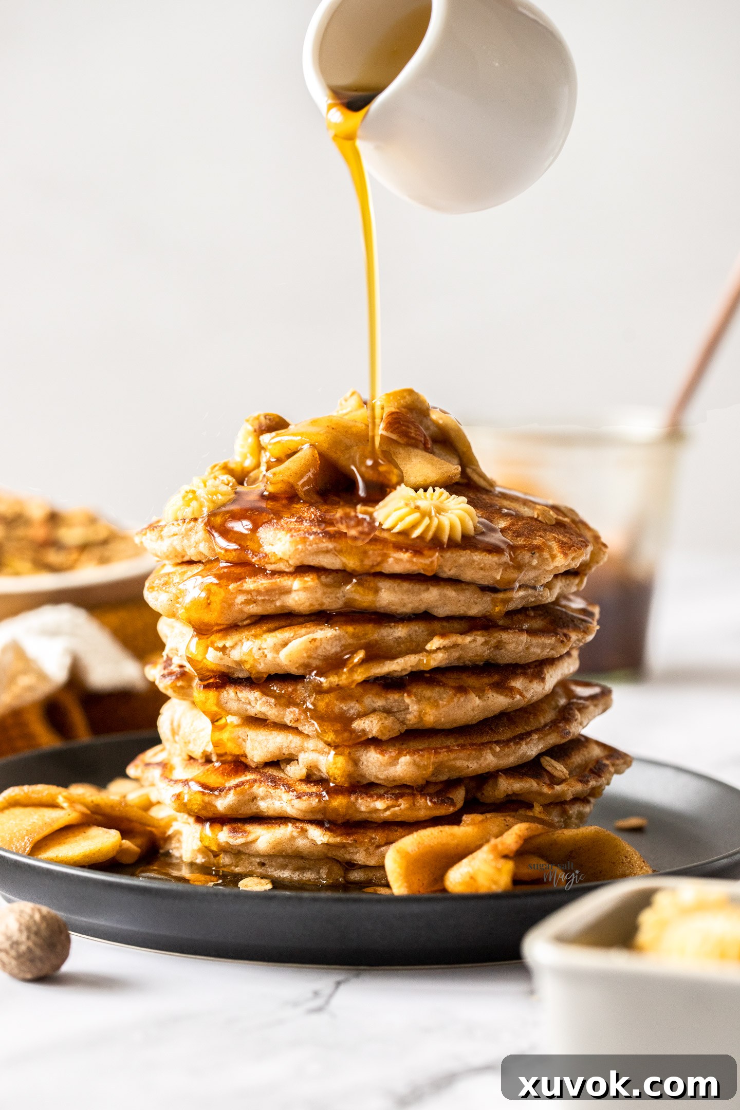 Maple syrup being poured over a stack of pancakes.