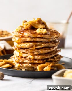 A stack of pancakes topped with apples and butter.