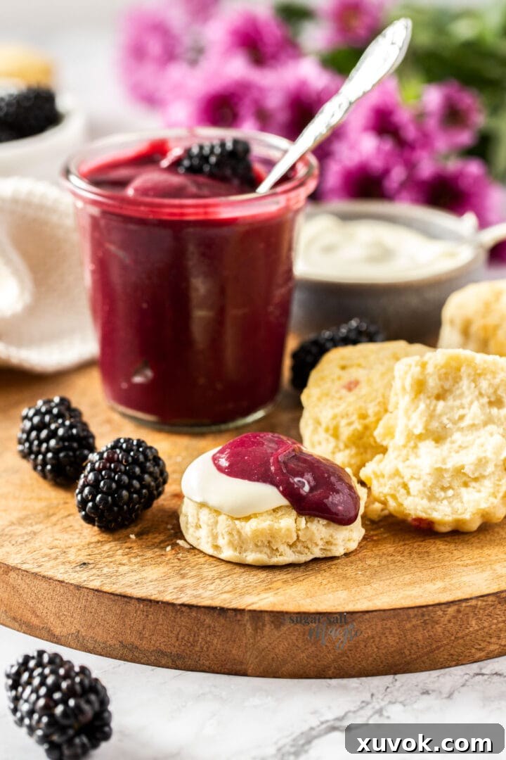 A perfectly baked scone, split in half and generously topped with clotted cream and homemade blackberry curd, presented on a rustic wooden board, inviting a delightful indulgence.