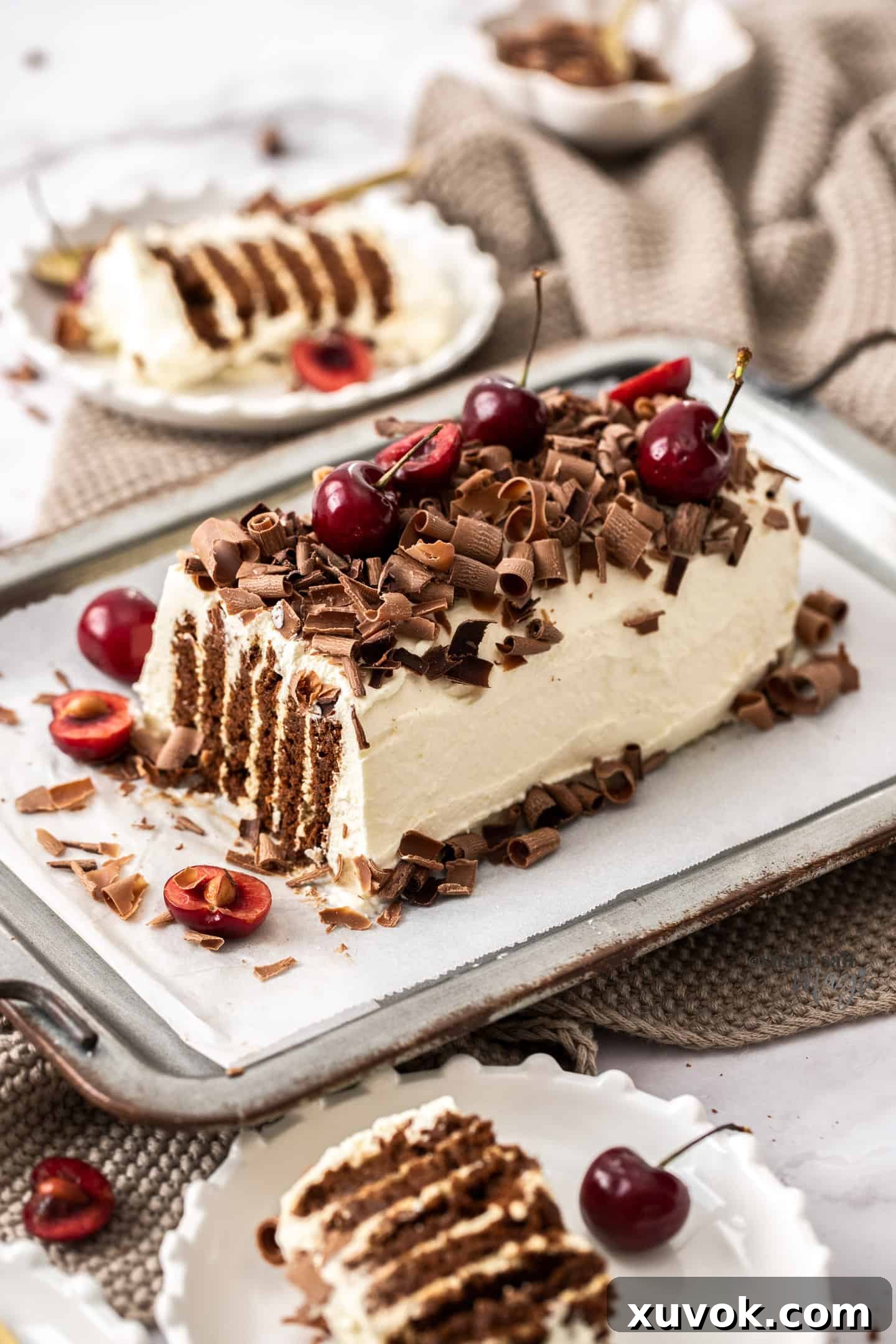 A freshly made chocolate ripple cake, beautifully covered in whipped cream and garnished with chocolate curls and cherries, resting on a rustic metal tray platter, ready for serving.