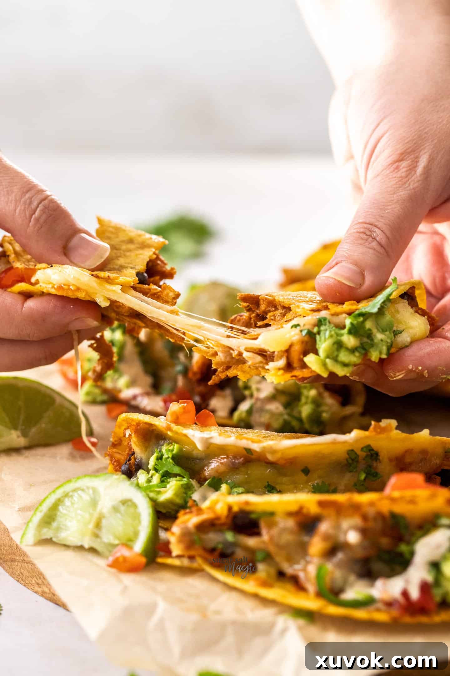 A baked chicken taco being torn apart, revealing the melted, gooey cheese and succulent chicken filling.