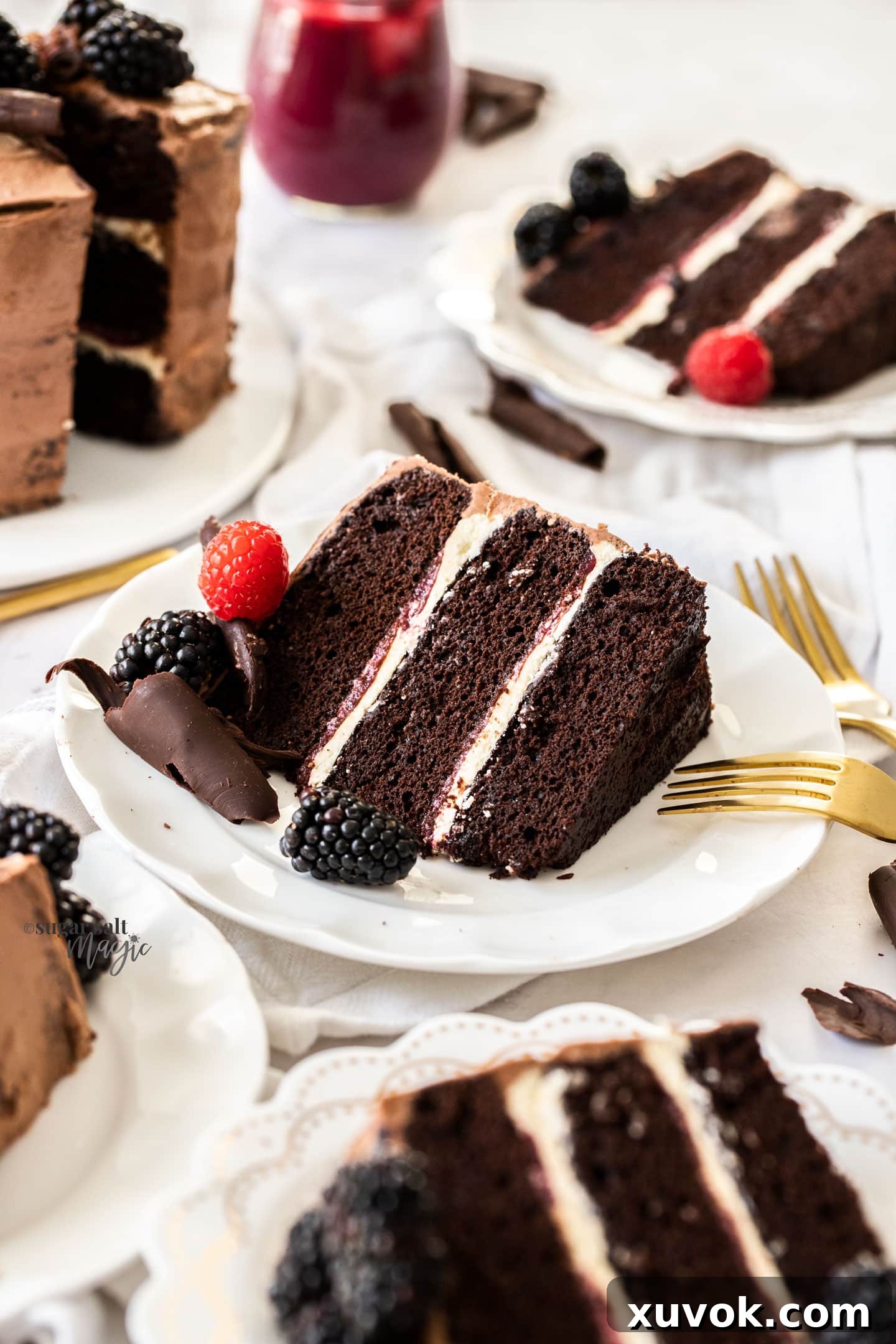 A perfectly portioned slice of the three-layer chocolate cake, showcasing its rich layers and creamy filling, presented on a pristine white plate alongside other delectable slices.