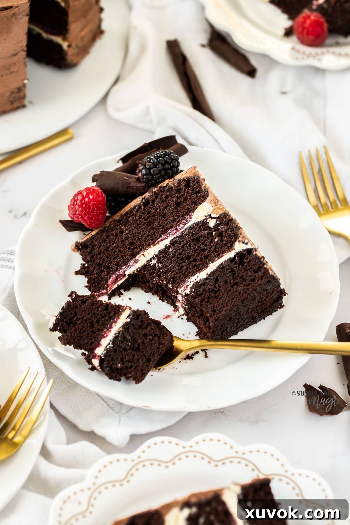 A delectable slice of three-layer chocolate cake on a white plate, with a fork having just cut out a perfect bite, emphasizing its moist texture and rich layers.