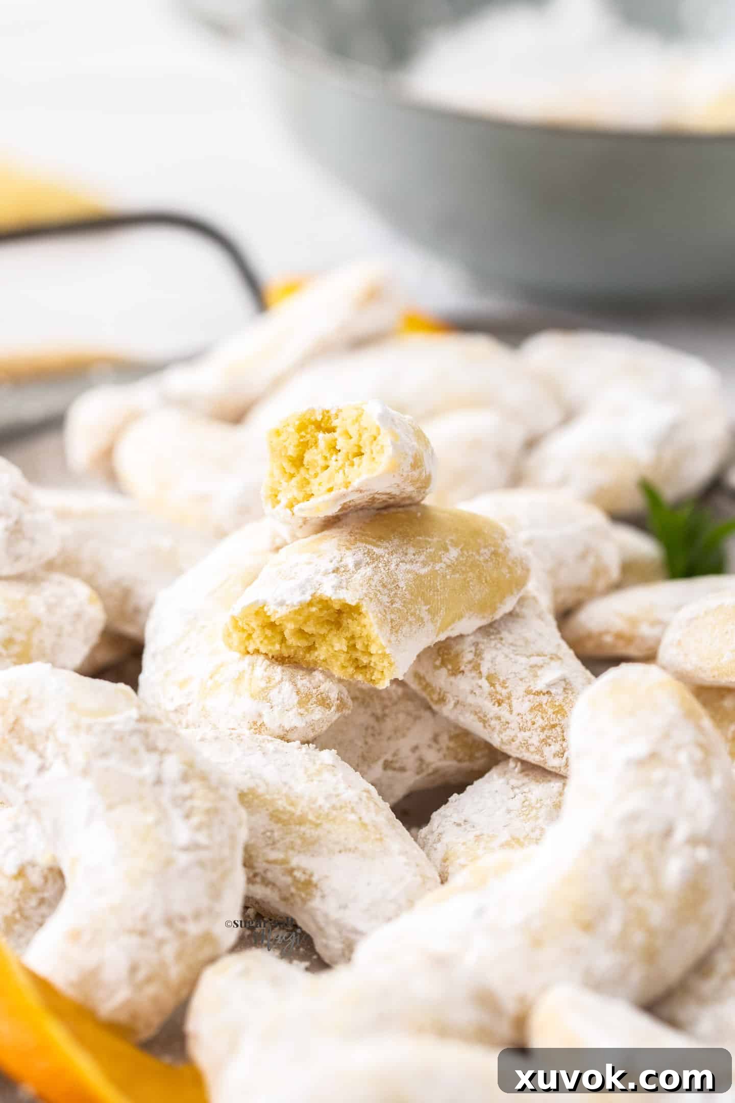 A single orange almond crescent cookie gently broken in half, revealing its tender, crumbly, and buttery interior texture, inviting a bite.