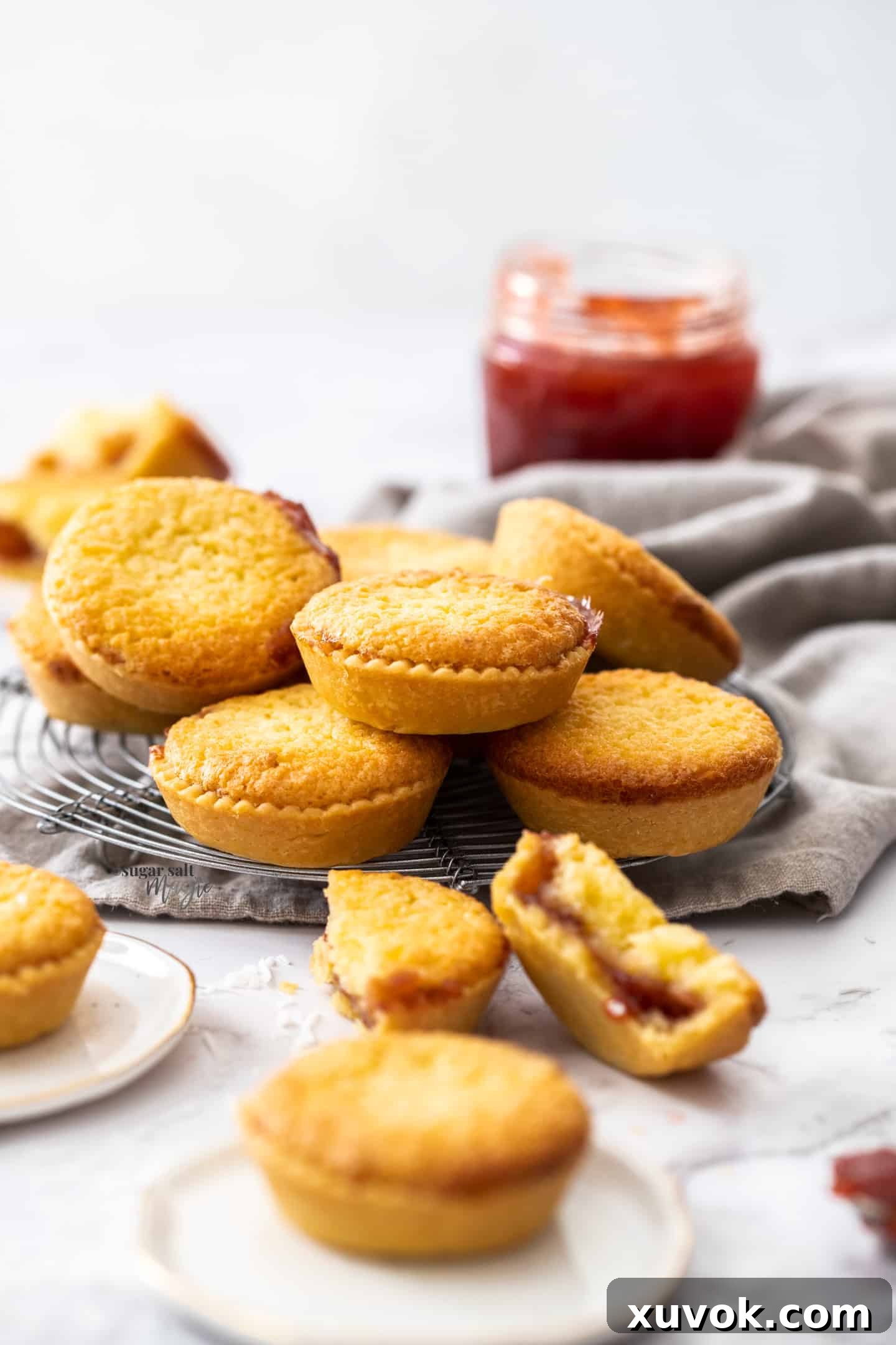 A stack of golden-brown coconut tartlets on a small wire rack, showcasing their perfectly baked pastry and luscious filling.