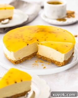 A beautiful passionfruit cheesecake with slices cut from it on a white platter.