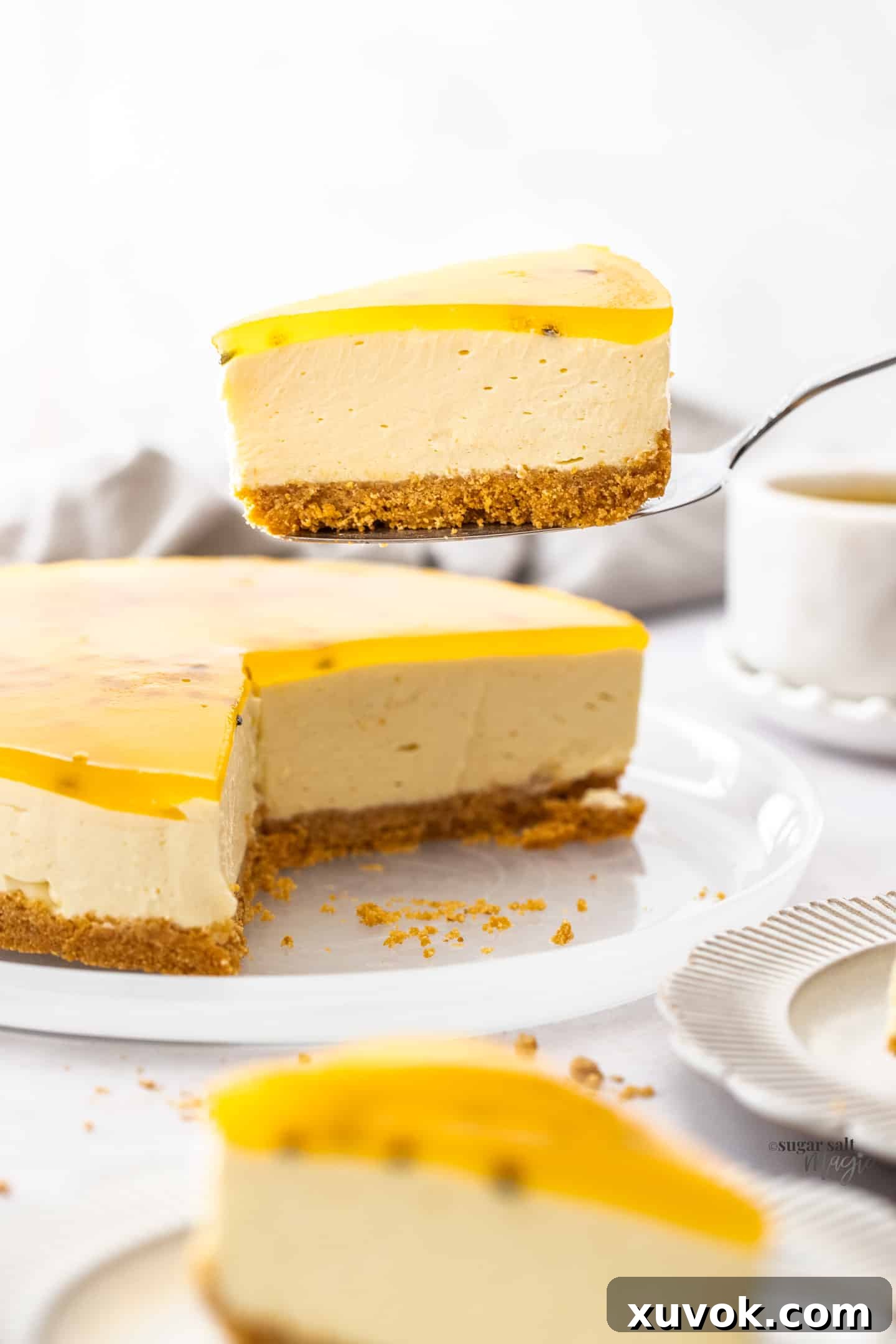 A slice of no-bake passionfruit cheesecake being gently lifted from the serving plate with a spatula, showcasing its perfect set.