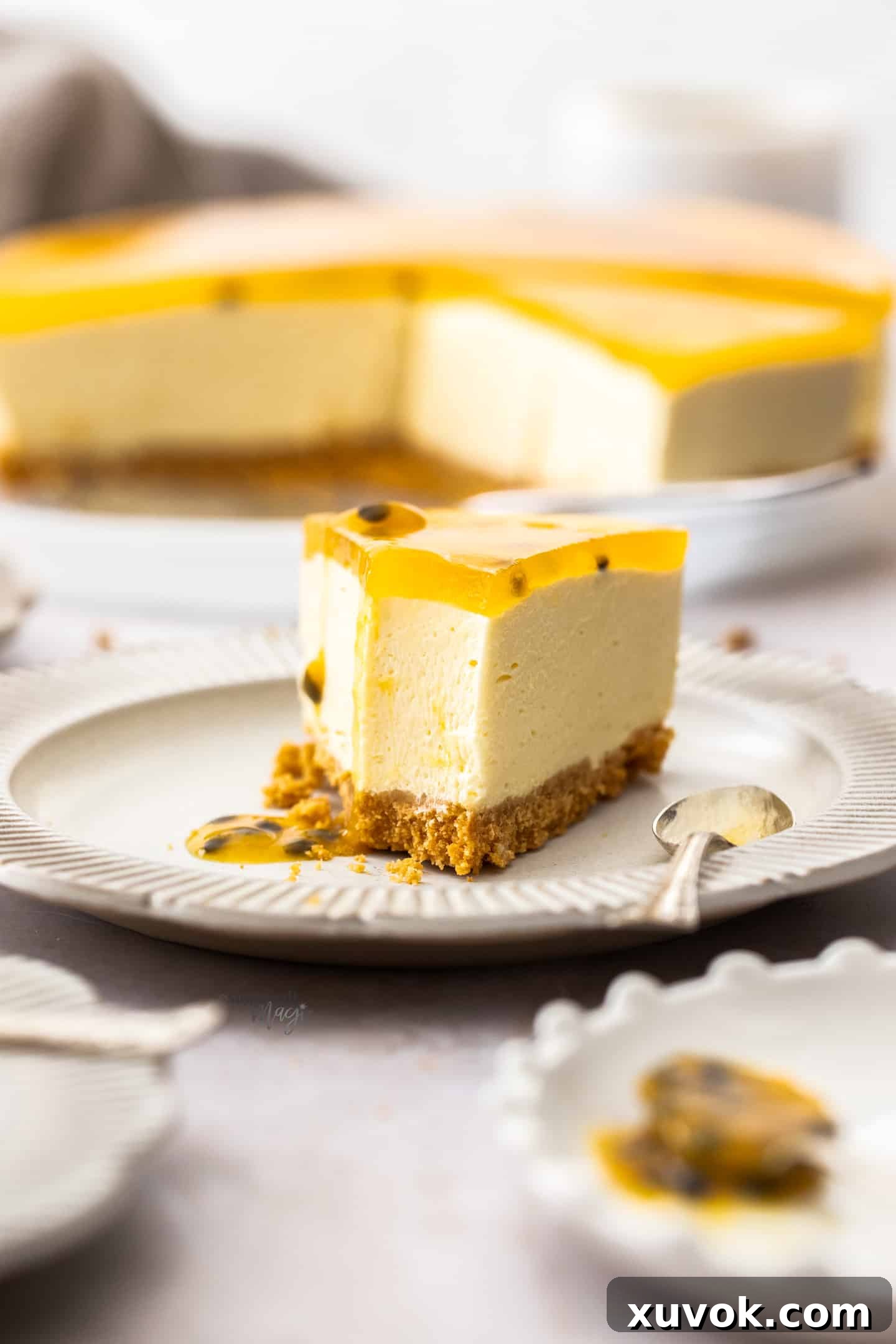 A slice of passionfruit cheesecake with a spoonful taken out of it, revealing its creamy texture and crunchy base.