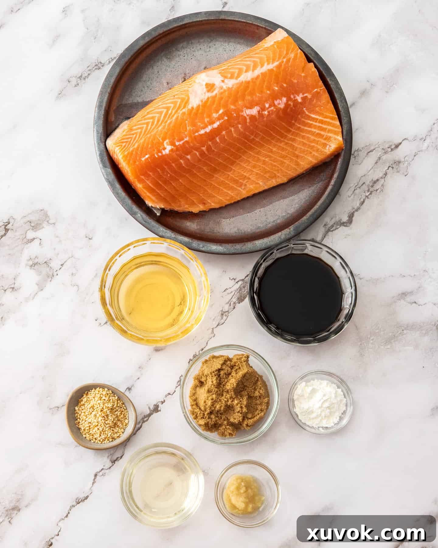 All the fresh ingredients for baking teriyaki salmon, neatly arranged on a pristine marble countertop, ready for preparation.