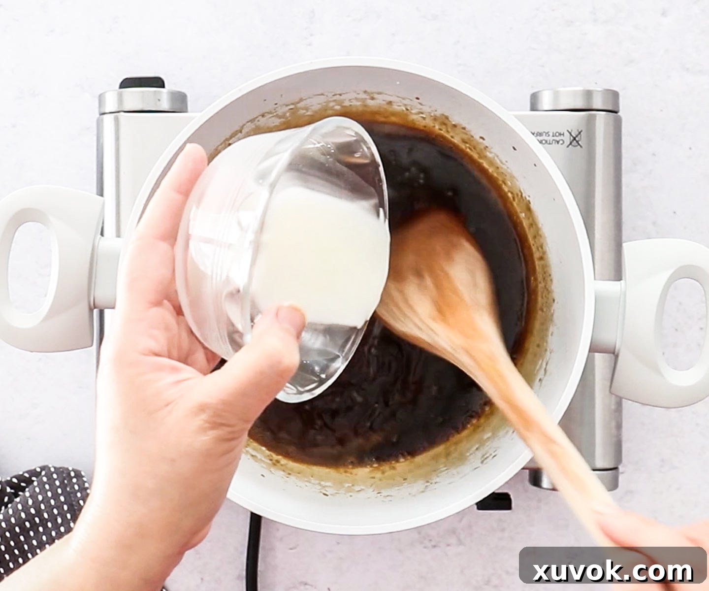 A cornflour slurry being carefully added to the simmering teriyaki sauce in the pan, initiating the thickening process for a rich glaze.