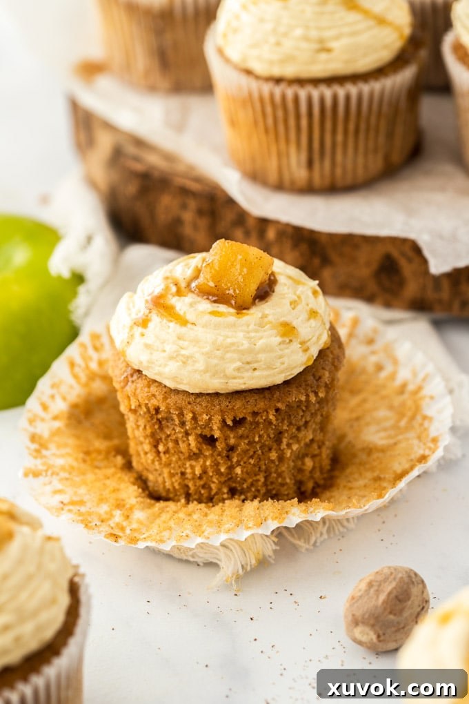 A cupcake with the paper peeled away showing the moist texture of the apple pie cake. 