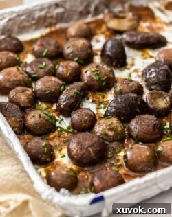Roasted miso mushrooms on a foil lined baking tray scattered with chives.