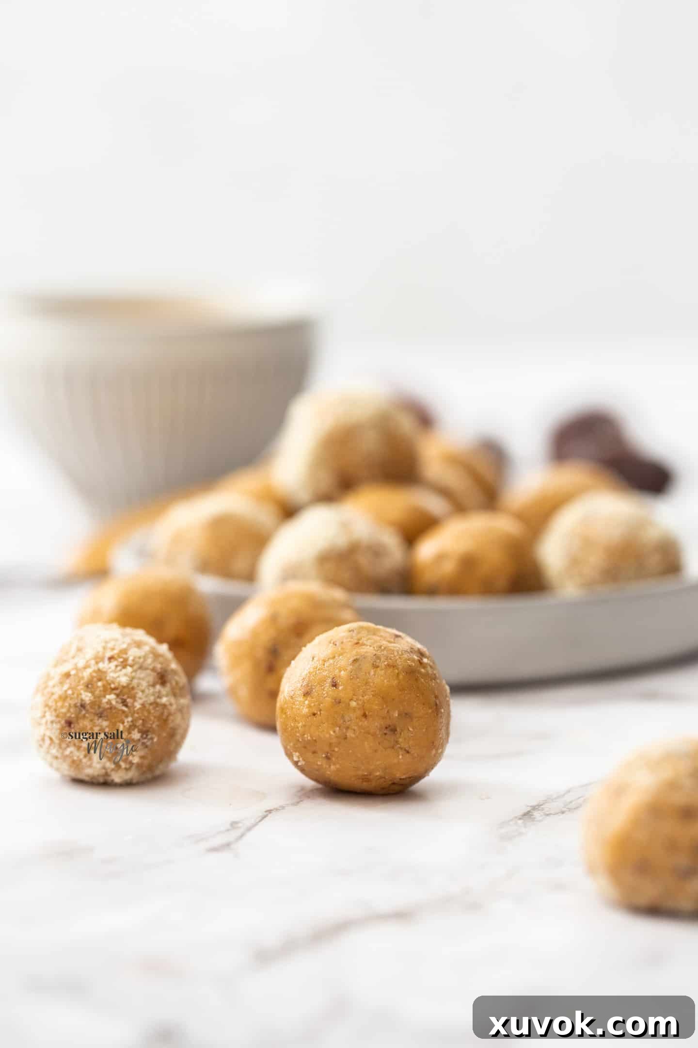 Peanut butter bliss balls sitting on a marble benchtop, ready to be enjoyed. A perfect healthy snack.