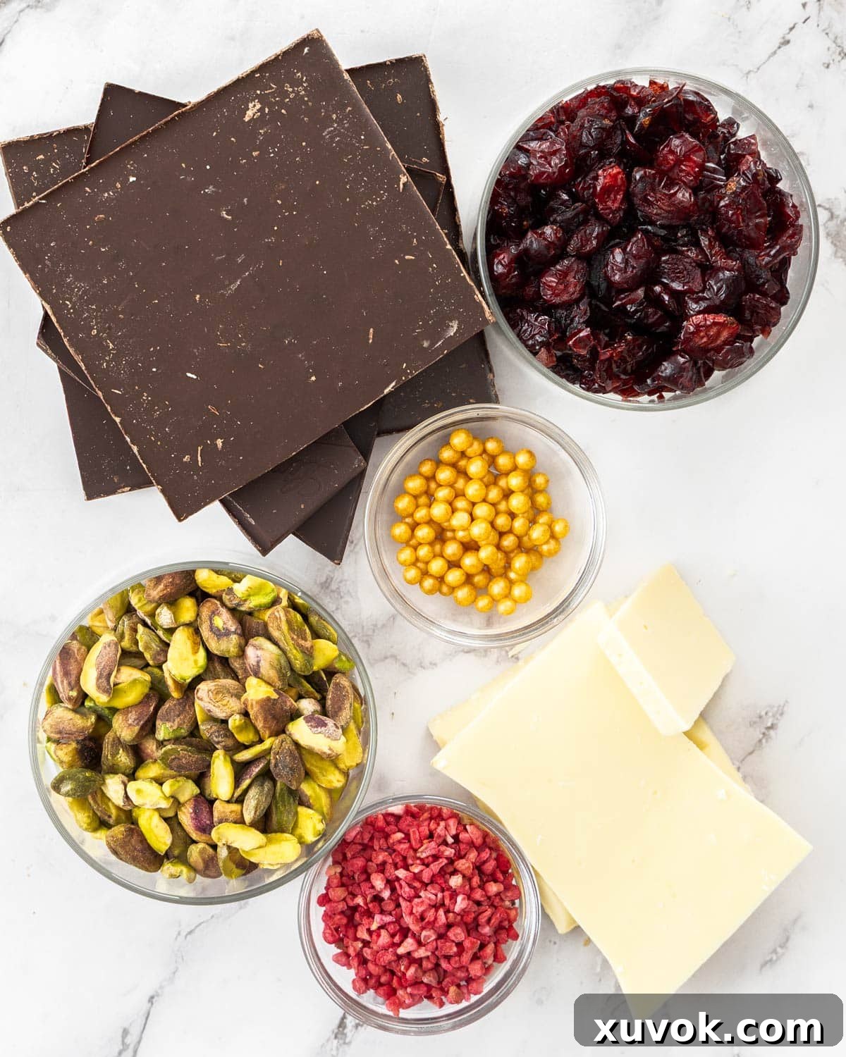 Ingredients for chocolate Christmas bark laid out, including various chocolates, nuts, and dried fruits.