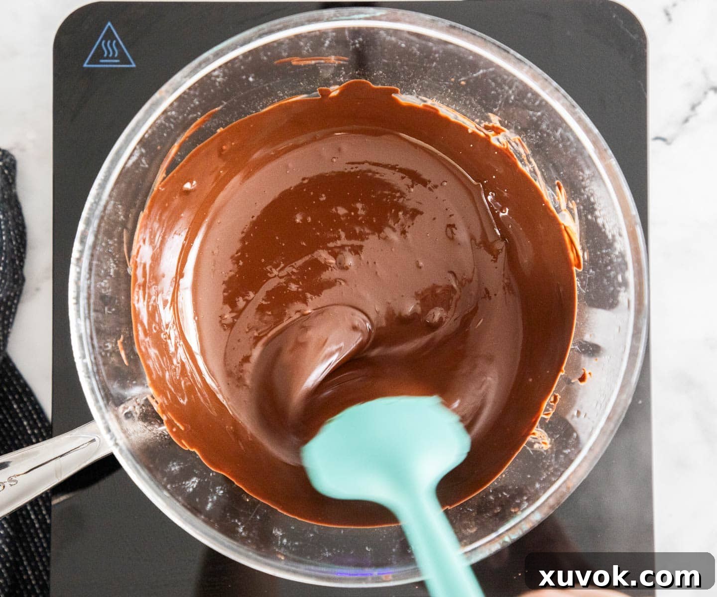 Melting dark chocolate in a glass bowl over a saucepan, demonstrating the double boiler method.