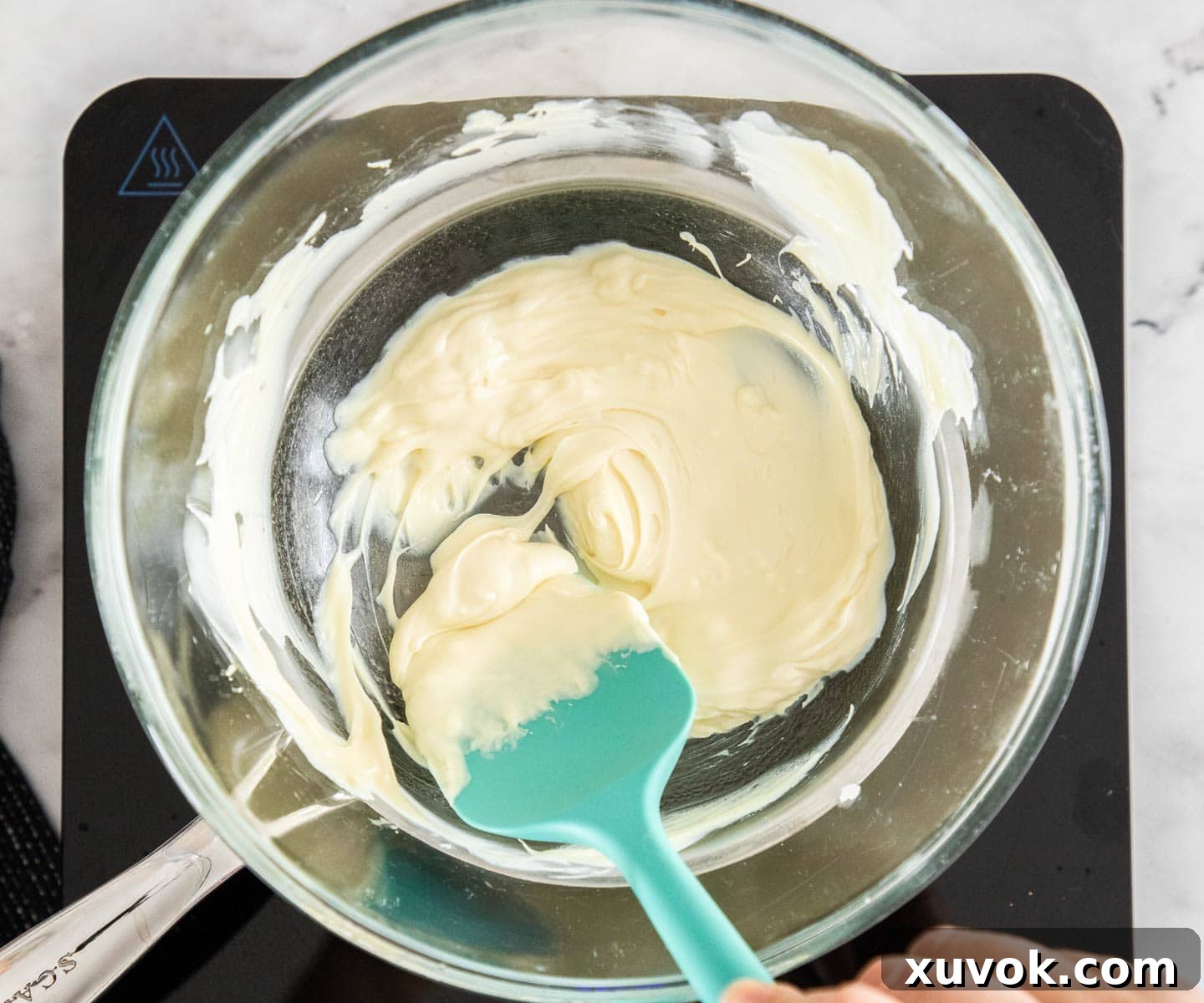 Melting white chocolate in a bowl over a saucepan, preparing for marbling.