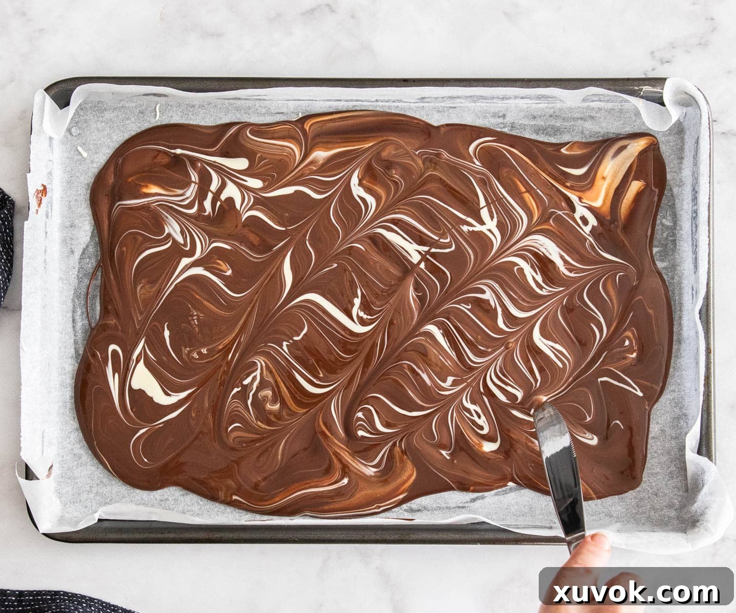 The white chocolate beautifully swirled through the dark chocolate on a baking tray, creating a marbled effect.