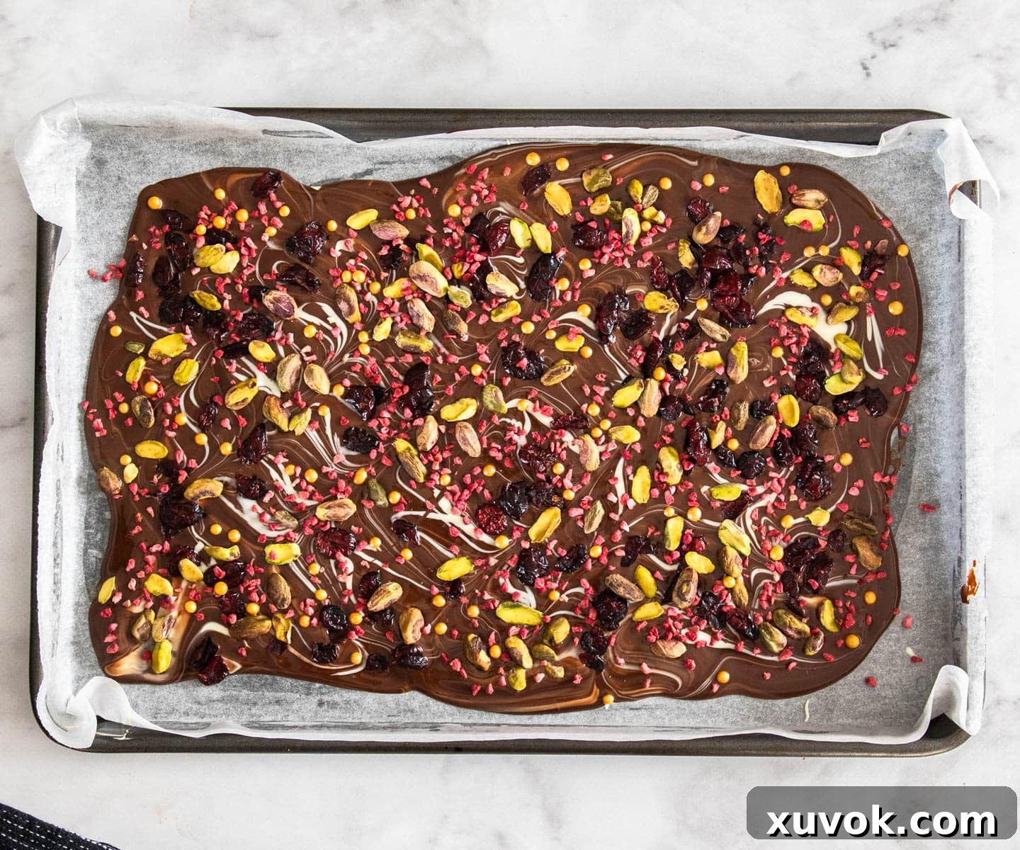 The chocolate Christmas bark, vibrant with cranberries and pistachios, awaiting its chill time.